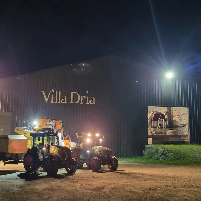 Galpão da Villa Dria à noite, com o nome na fachada e tratores da vindima